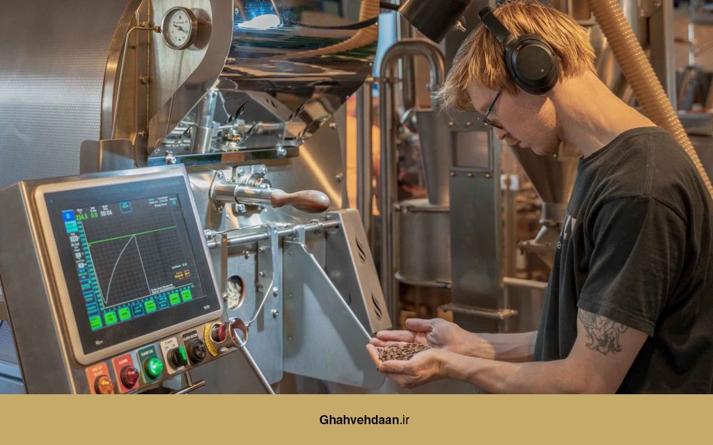 یک متخصص قهوه در حال تنظیم دستگاه رُست و بررسی پارامترهای مربوط به فرآیند رُست.